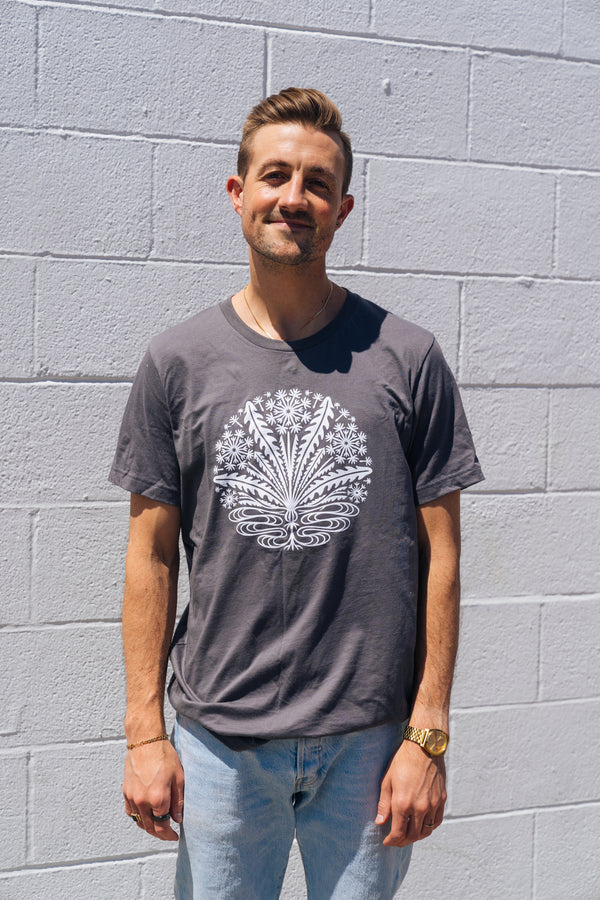 Man wearing a grey tee with white little brother dandelion logo on front