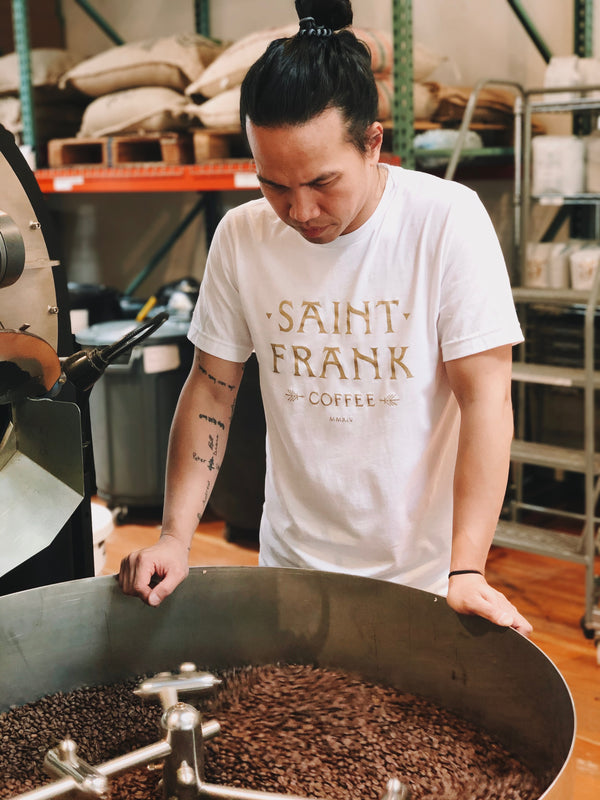 Man wearing Saint Frank Coffee Tee looking at coffee roaster